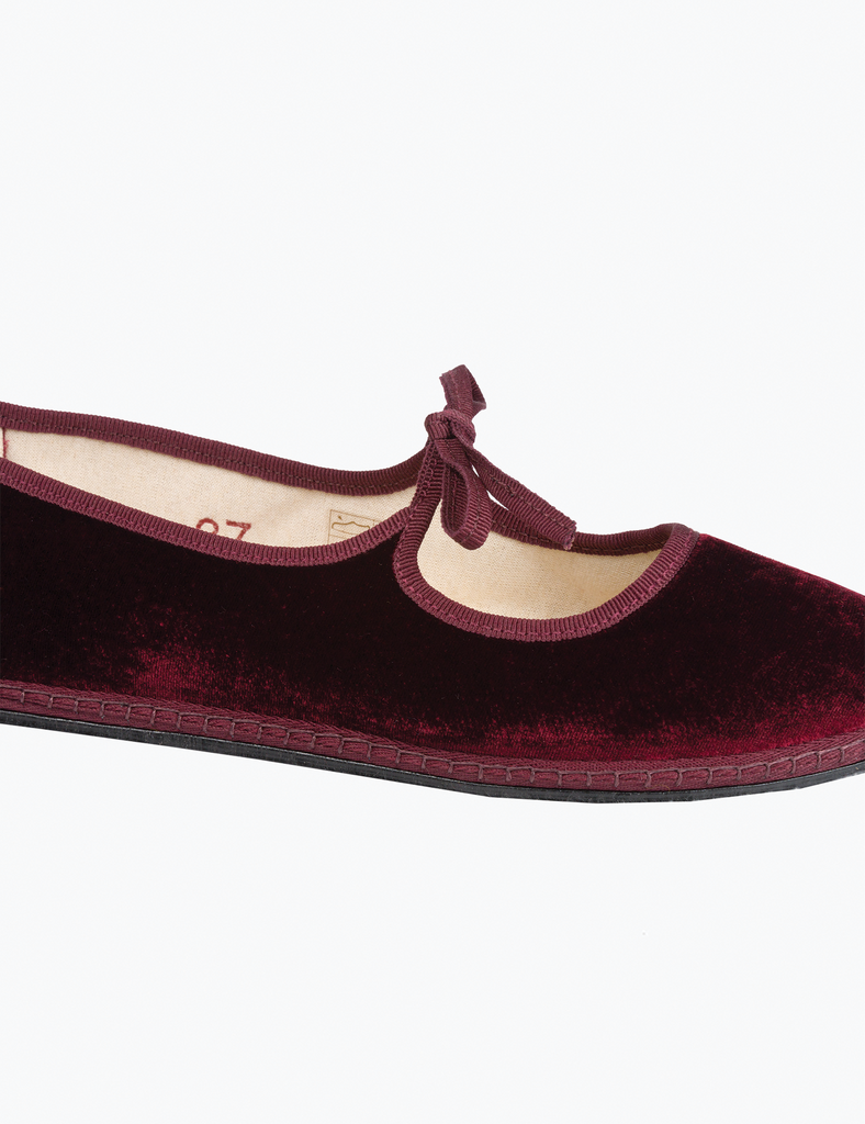 Maroon velvet shoe with a bow on a white background