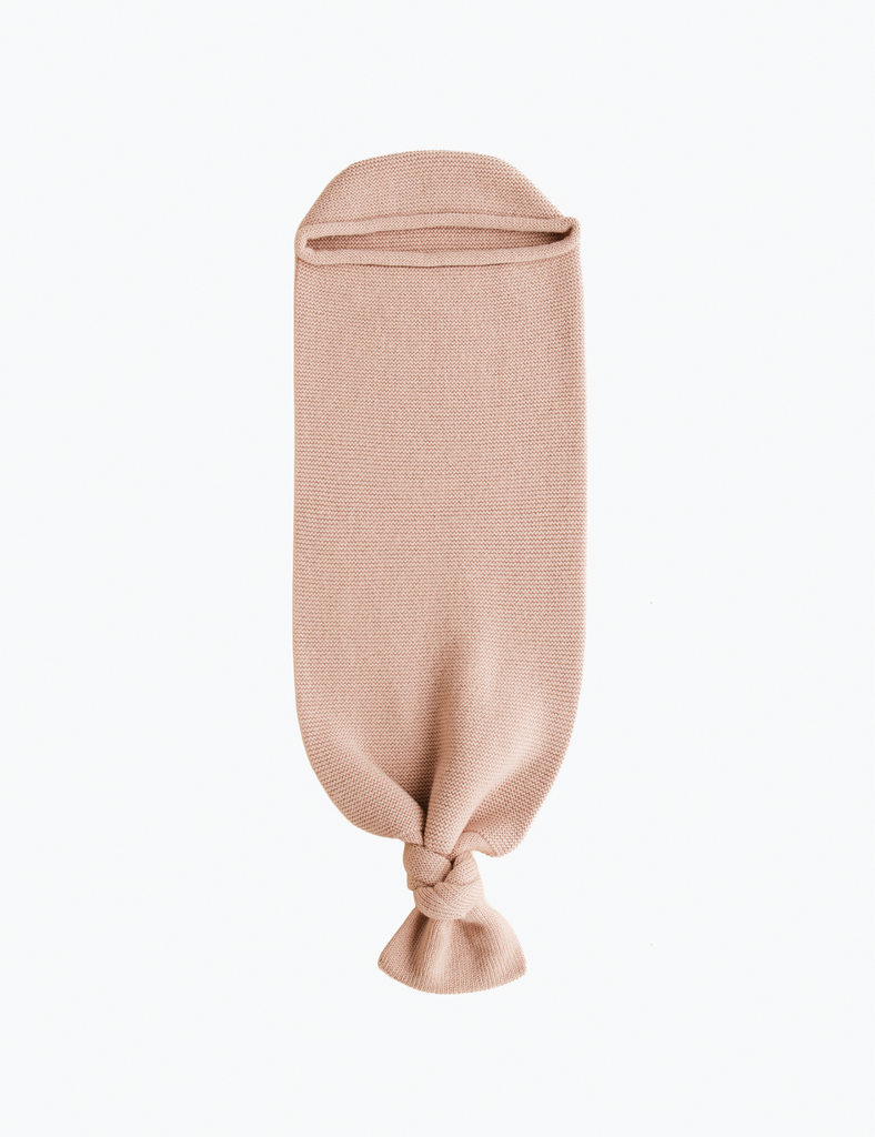 Image of a knitted baby sack in a light pink color in a white background.