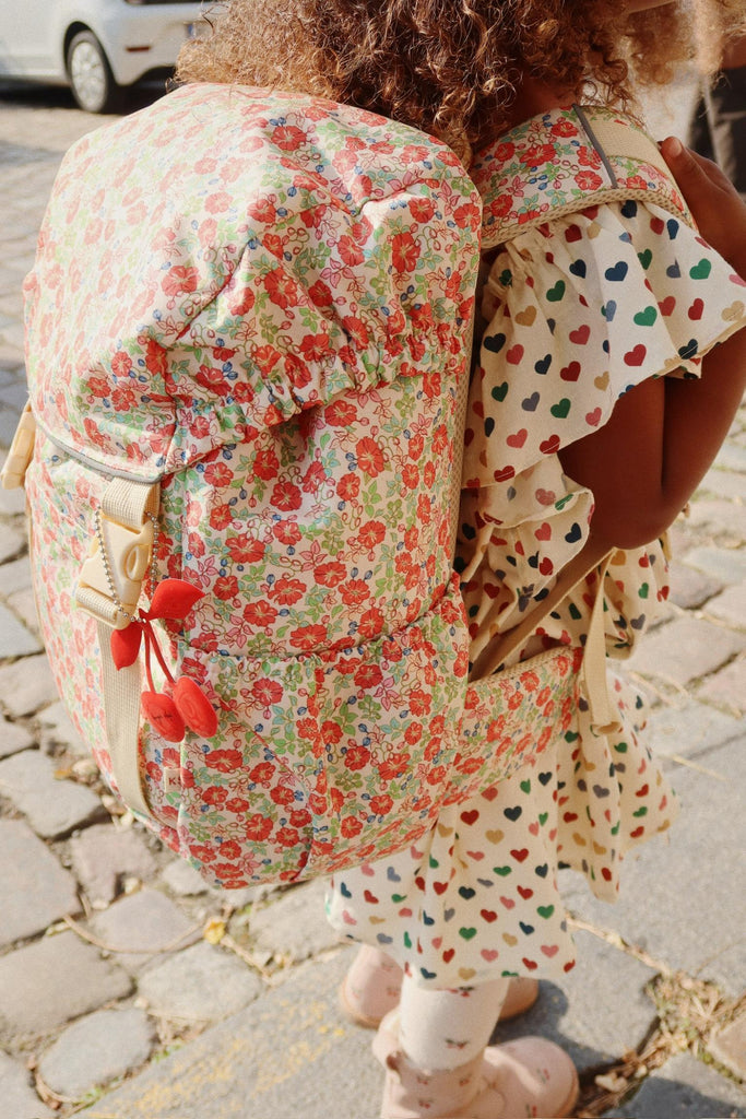 Person wearing a floral dress and backpack on a cobblestone street