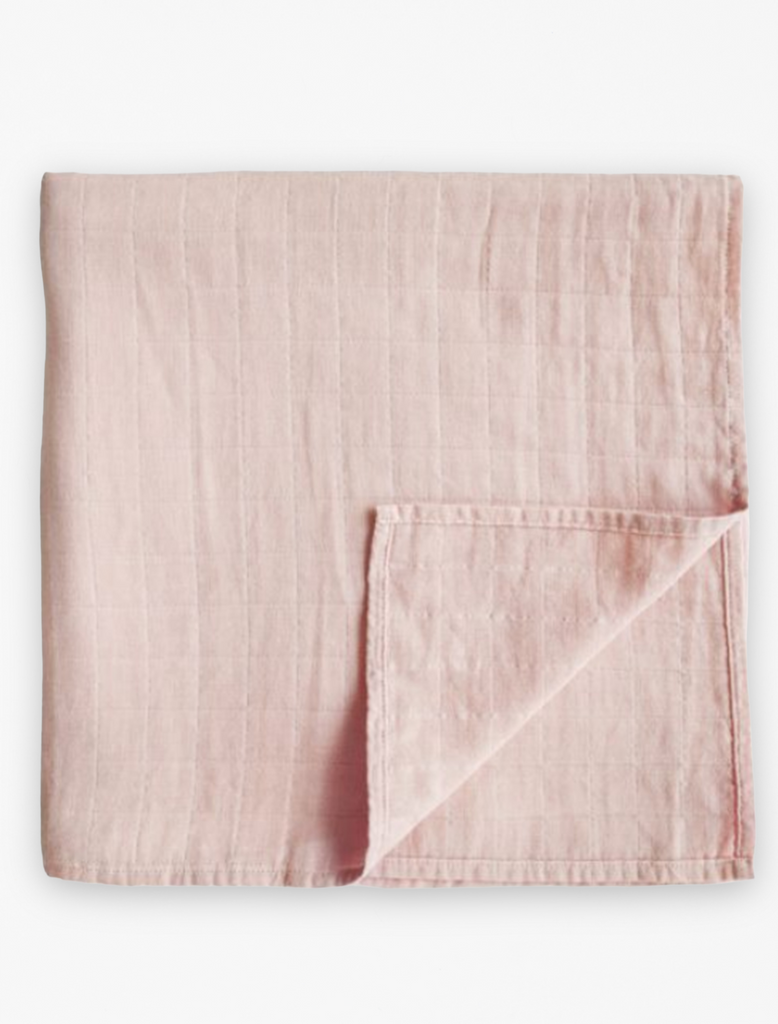 Mushie baby swaddle featured in rose vanilla color. Flat lay image.